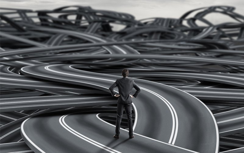 Man stands in front of a tangle of roads